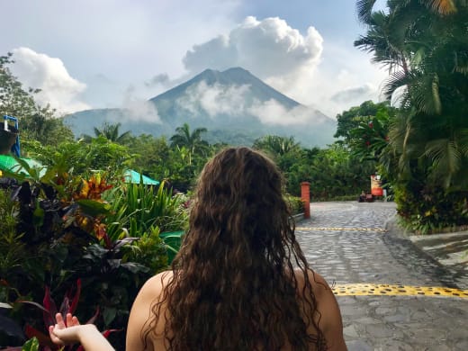 A student outside in Costa Rica, on a street with a view of a mountain.